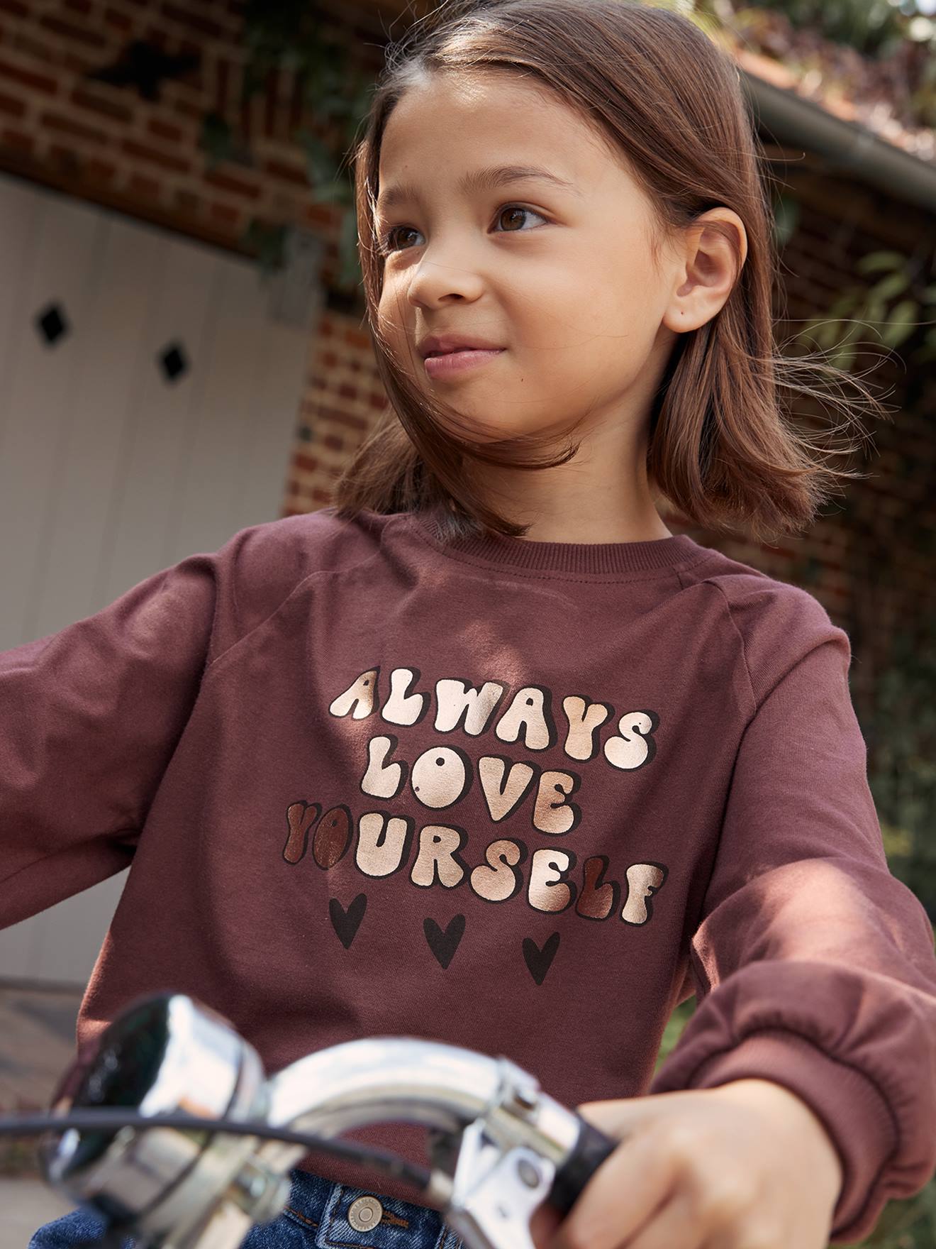 Camiseta evasê com mensagem vibrante e efeito metálico para meninas com maquiagem rosa.