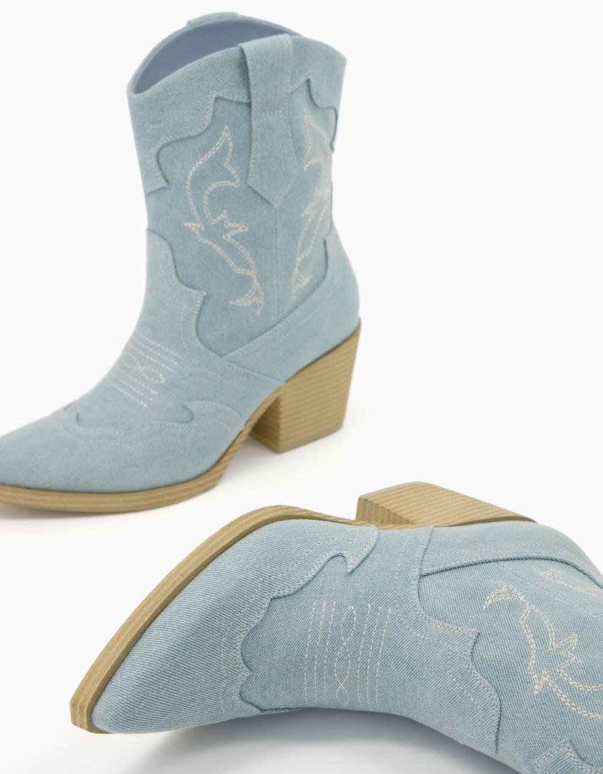 Botas de cano curto estilo cowboy em jeans com salto.