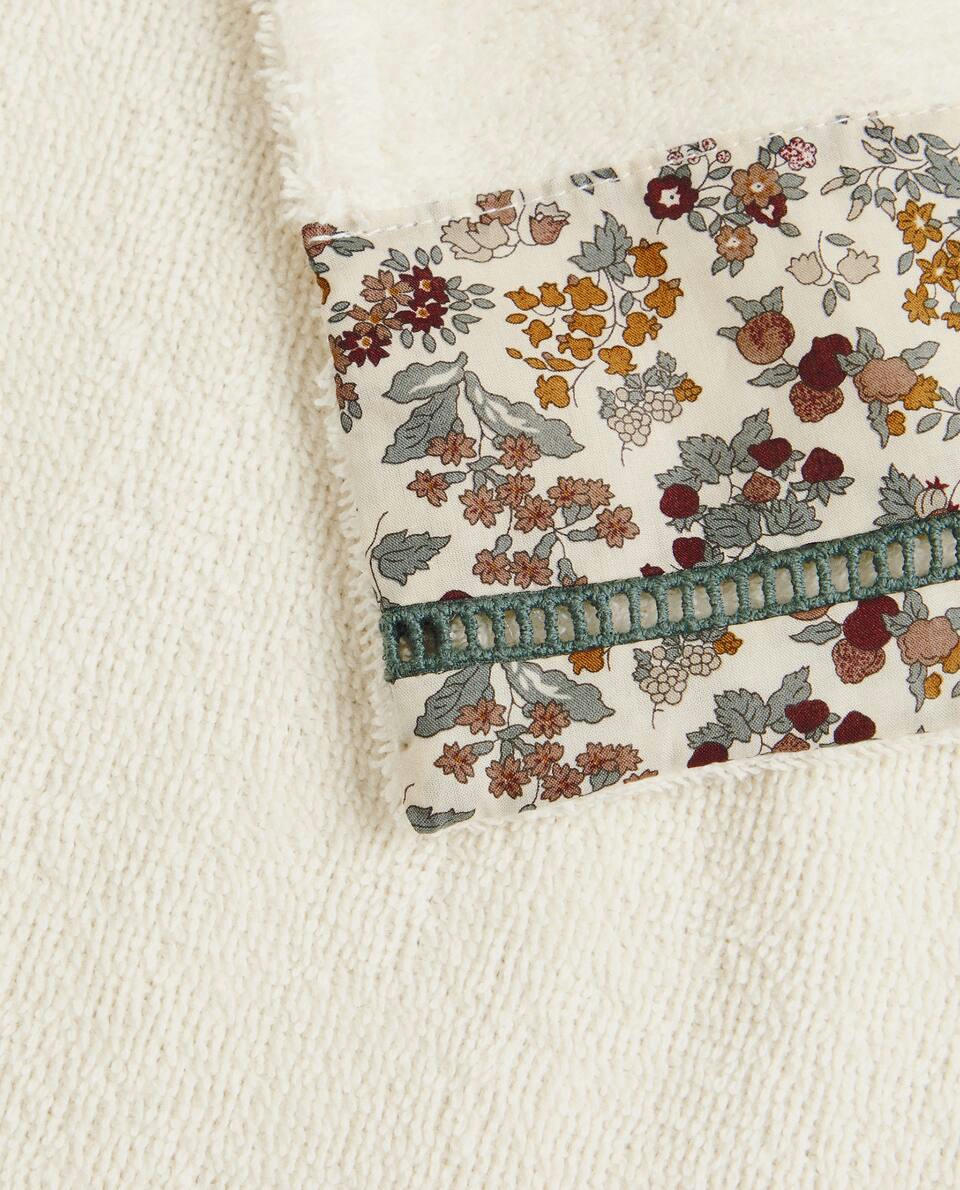 Toalha infantil de algodão com estampa floral e borda.
