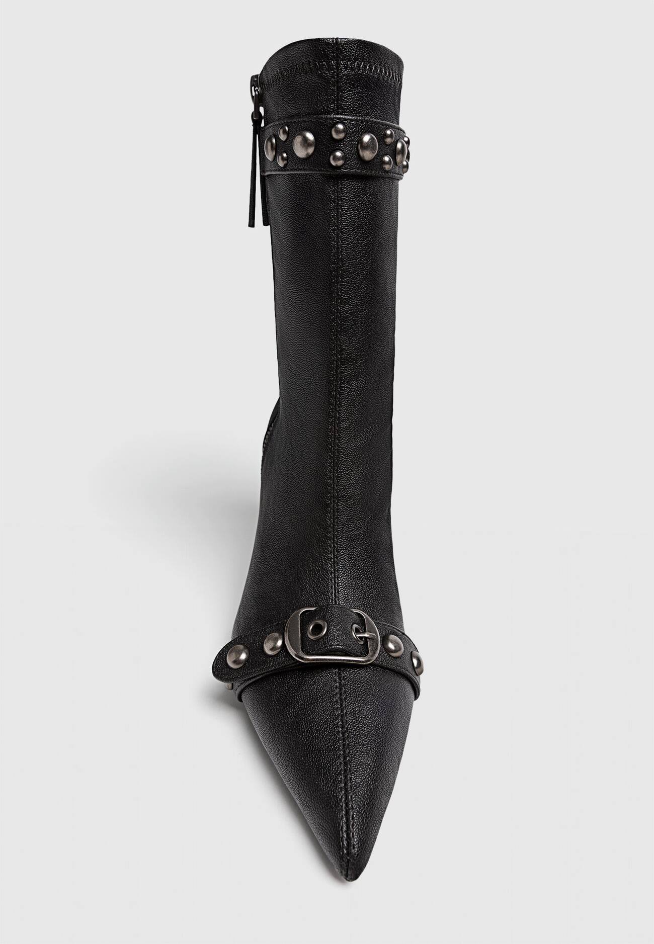 Botas de cano curto com tachas e fivelas em estilo desgastado.