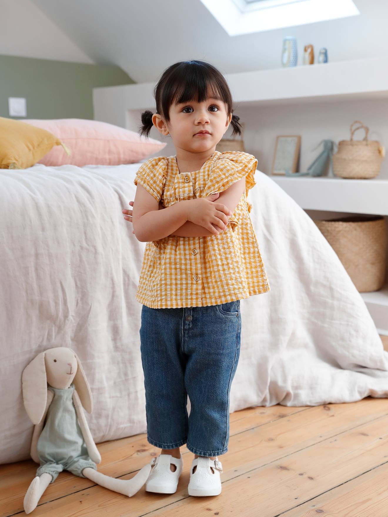 Conjunto infantil tamanho médio com blusa xadrez amarela e calça jeans de pernas largas.