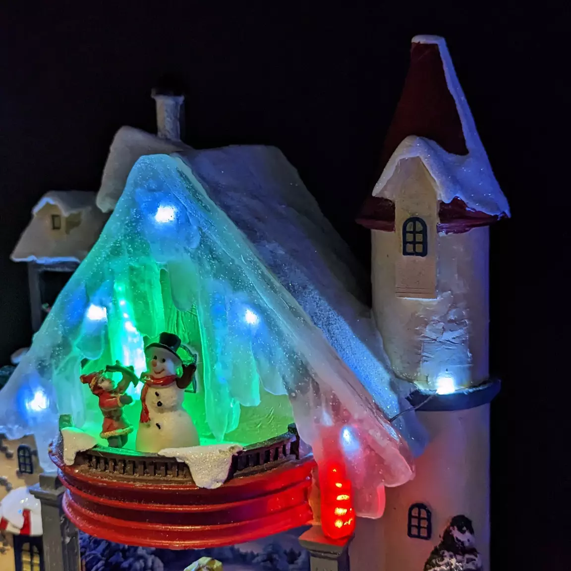 Maison du bonhomme de neige enneigée et illuminée à piles