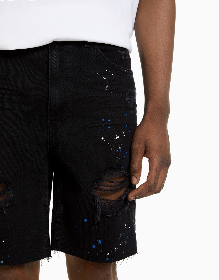 Bermuda jeans rasgada com respingos de tinta
