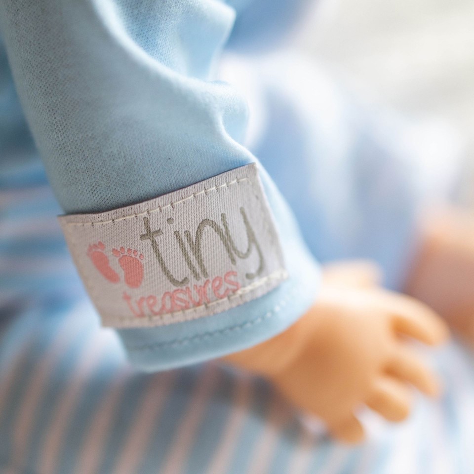 TINY TREASURES - Dukke med brunt hår og blåt bamse outfit