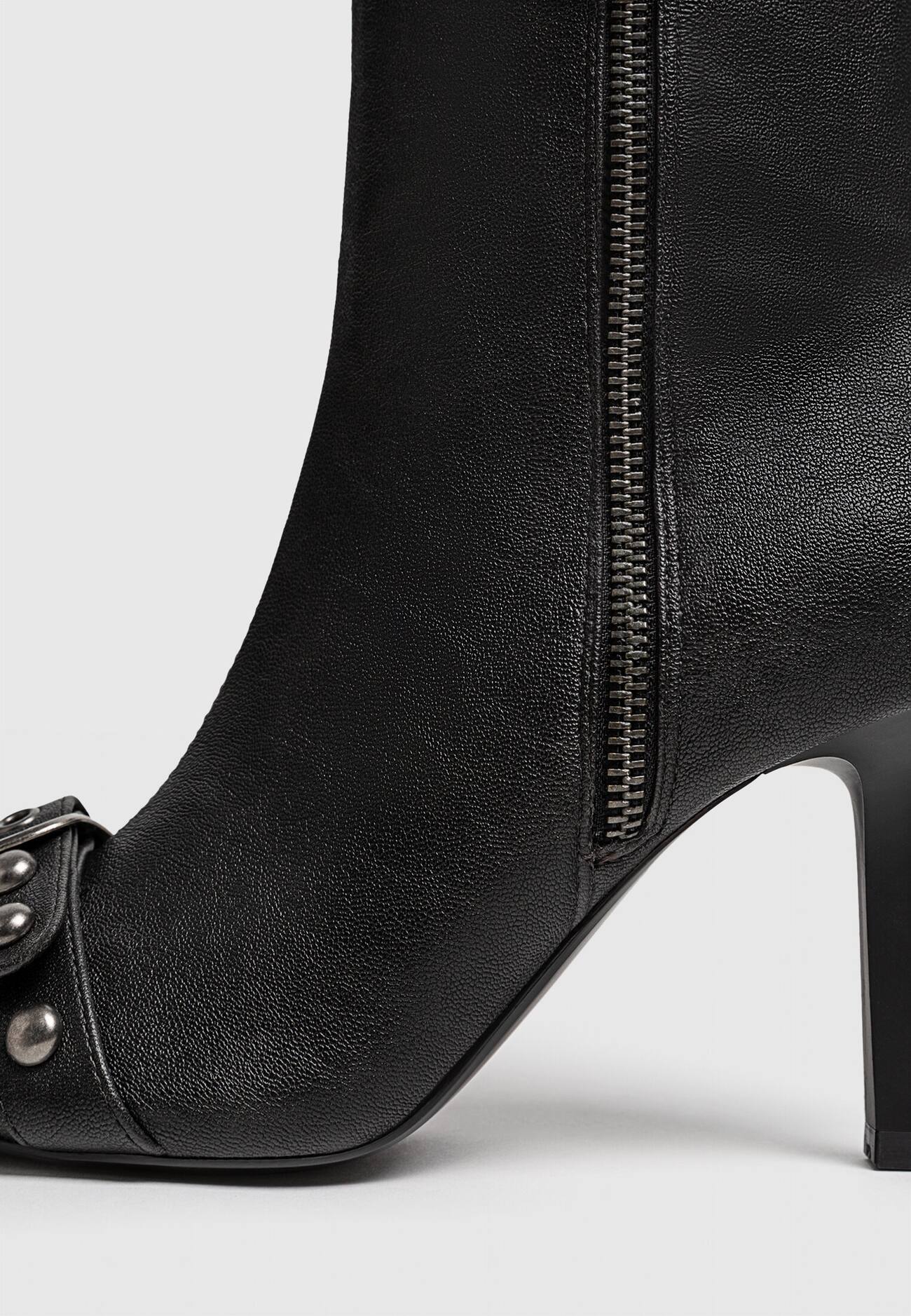 Botas de cano curto com tachas e fivelas em estilo desgastado.
