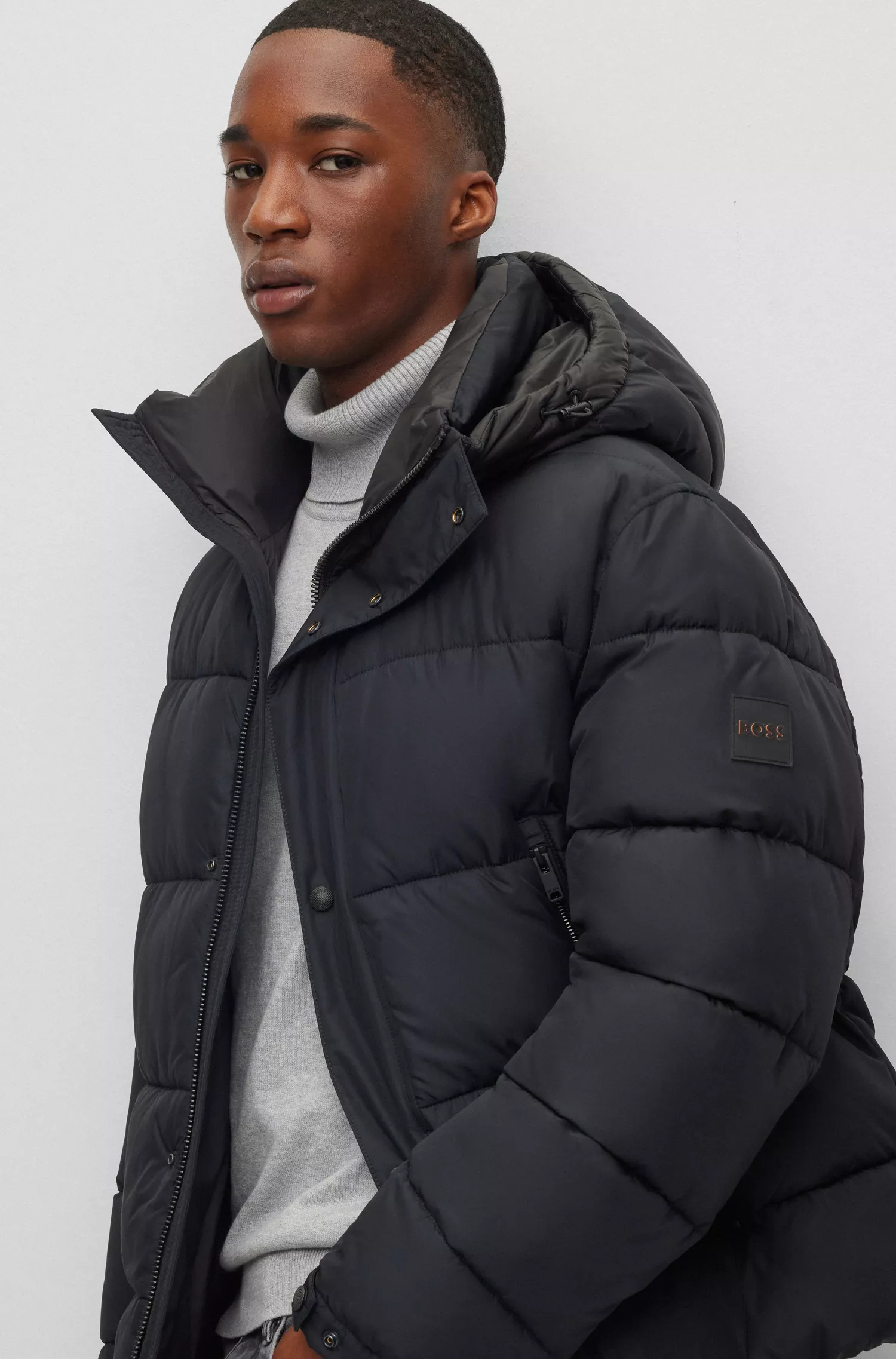 Jaqueta puffer com capuz BOSS laranja, repelente à água e com emblema da marca.