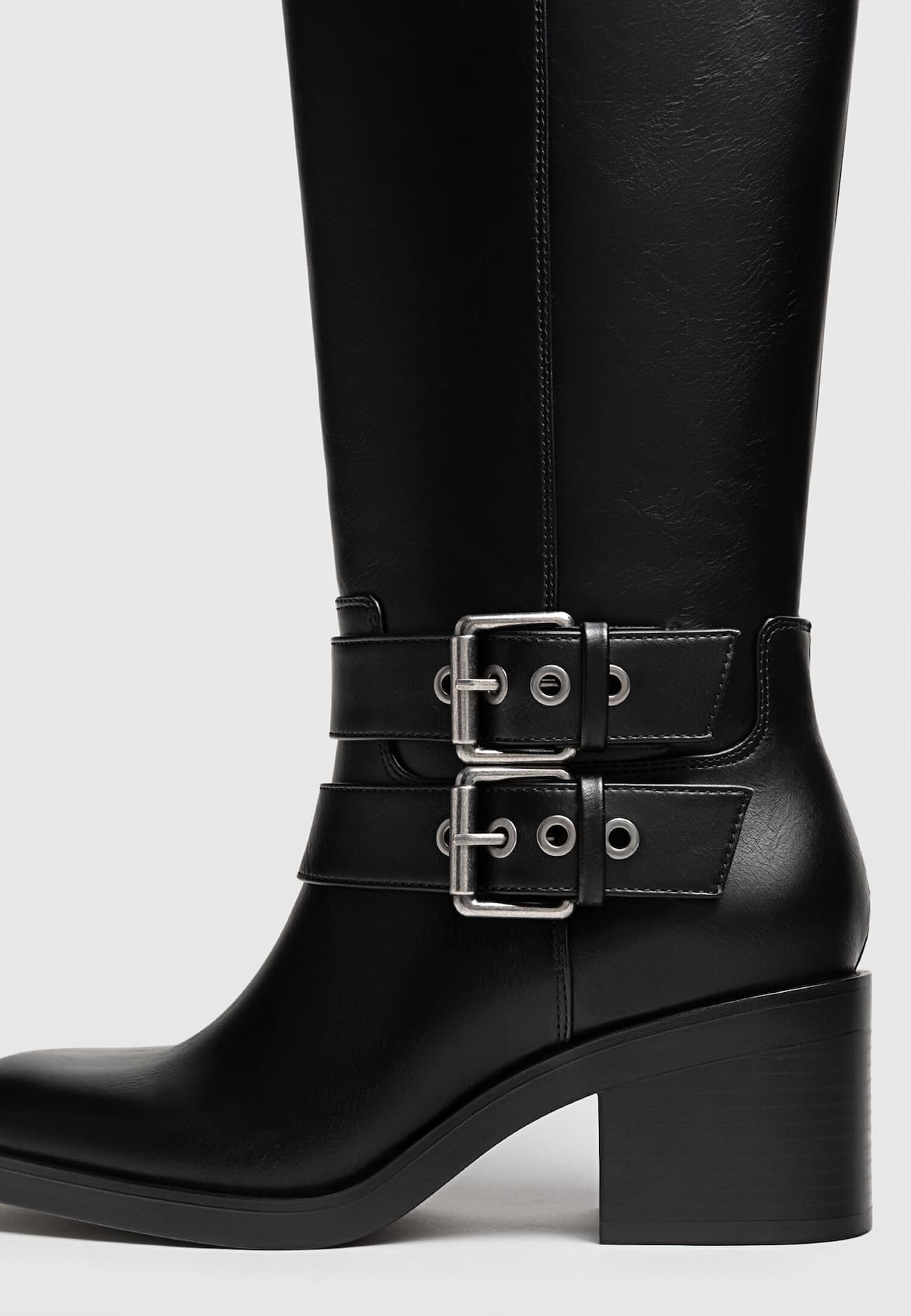 Botas pretas de motociclista com salto e fivelas.