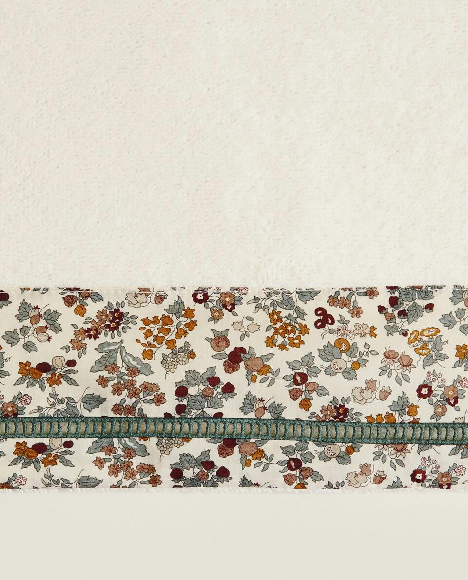 Toalha infantil de algodão com estampa floral e borda.