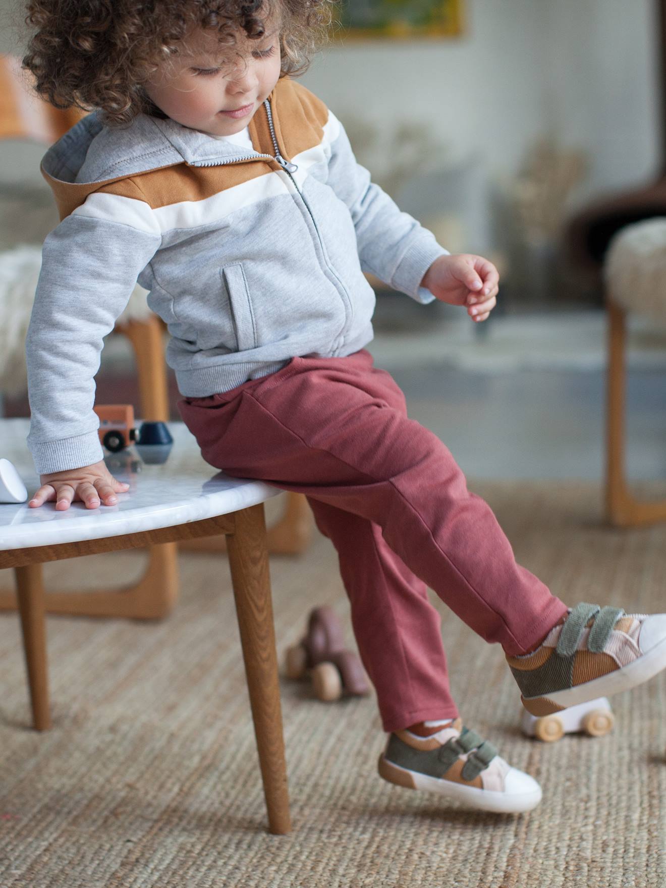 Jaqueta infantil masculina marrom-clara lisa com zíper, capuz e detalhes decorativos.