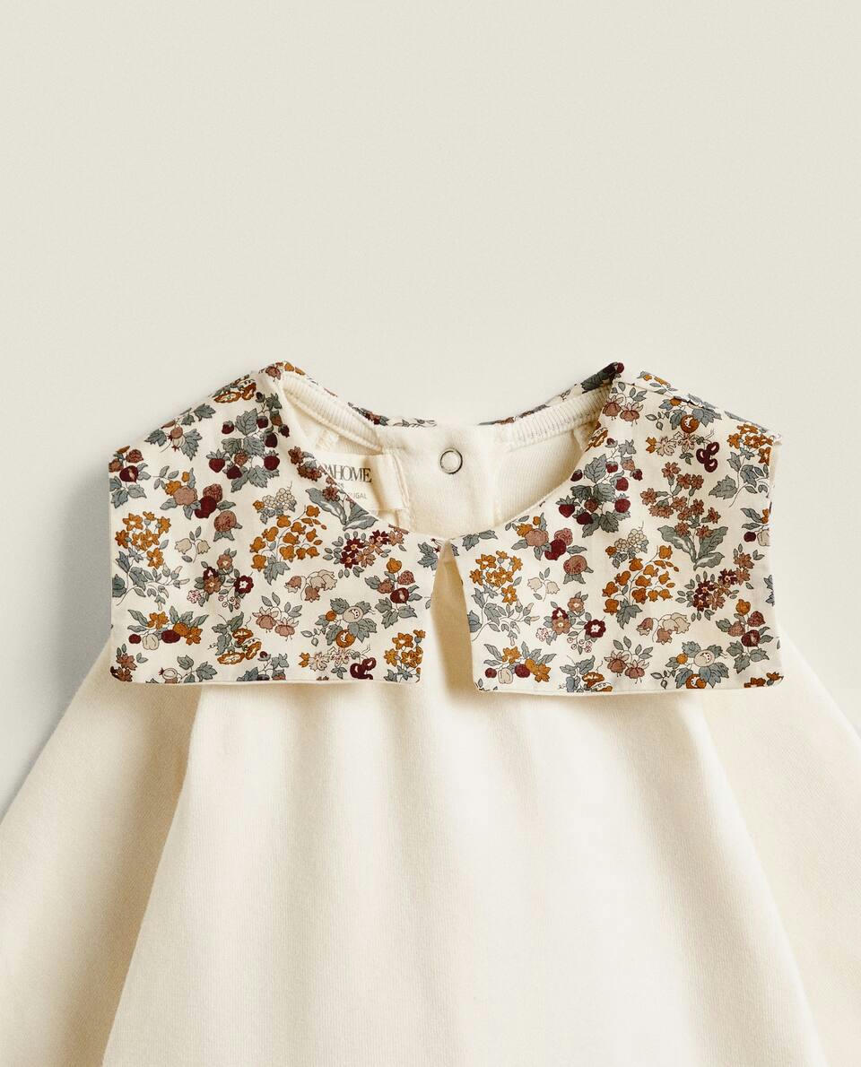Macacão infantil em tecido com estampa floral e detalhe de gola.