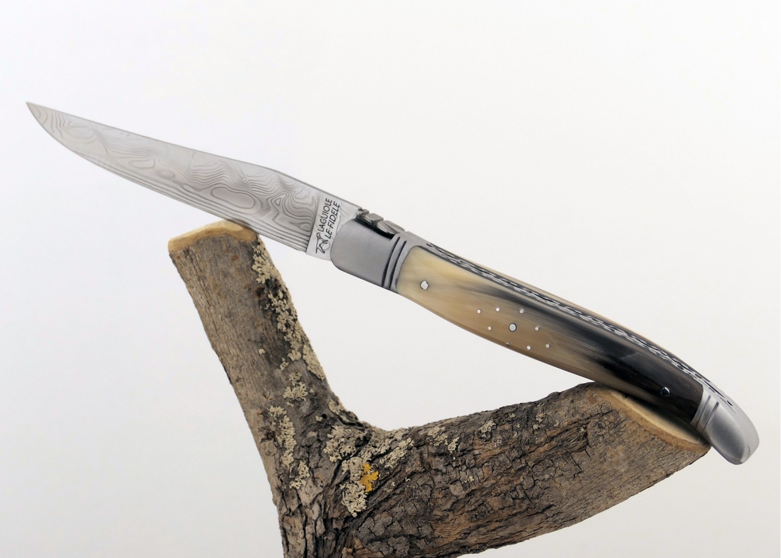 Couteau Laguiole prestige avec un manche en pointe de corne blonde et mitres en acier inoxydable et lame Damas