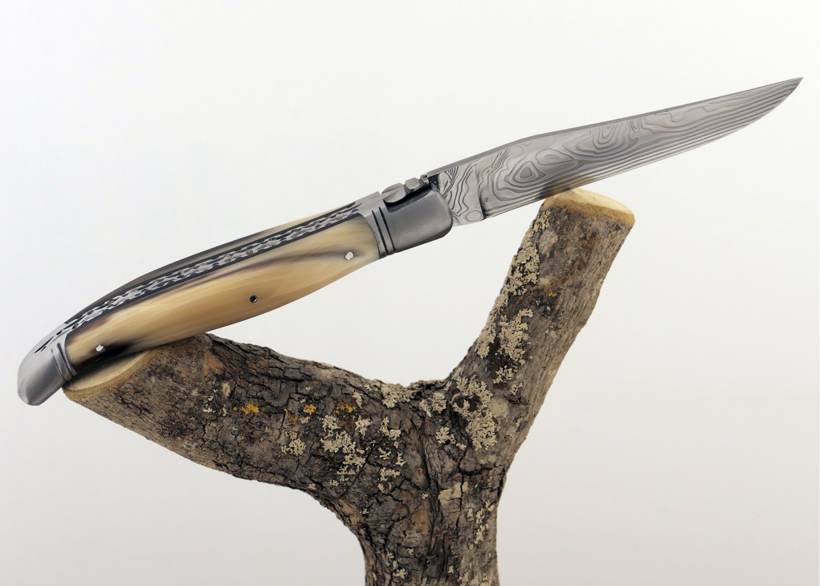 Couteau Laguiole prestige avec un manche en pointe de corne blonde et mitres en acier inoxydable et lame Damas