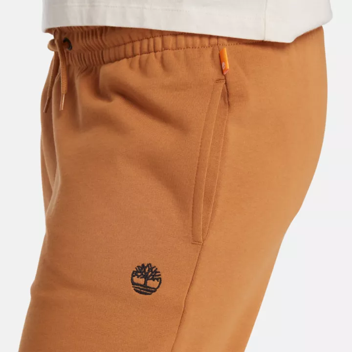 Calça de fato de treino feminina com bordado de árvore no tom amarelo escuro.