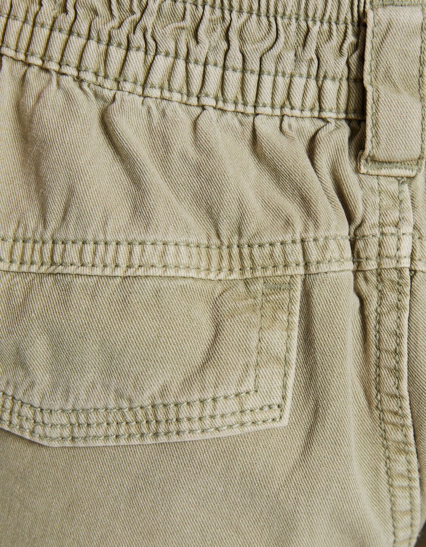 Calças de algodão com cintura franzida e bolsos.