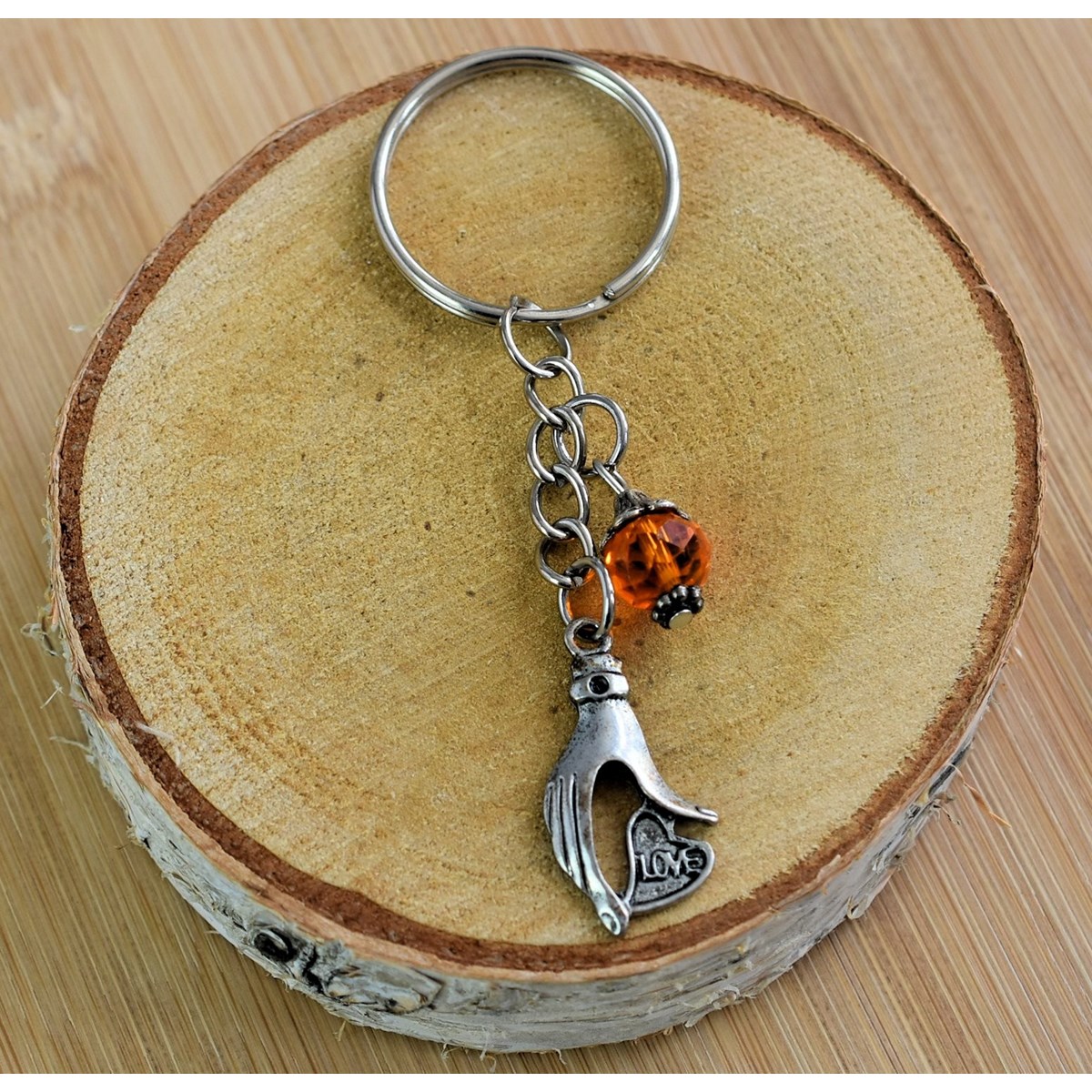 Porte-clés main qui tient un coeur love argentée et perle à facettes orange