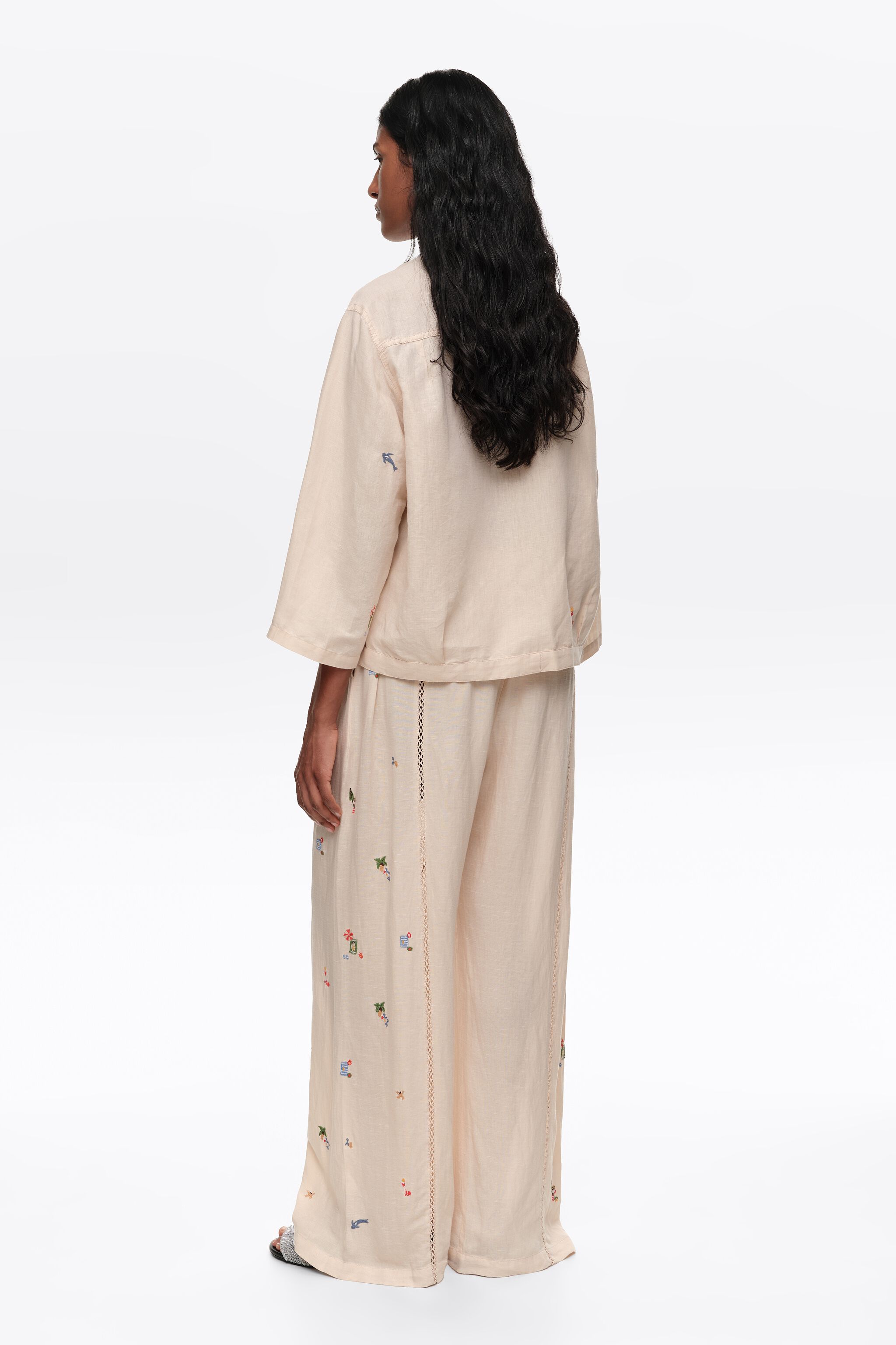 Calças largas de linho branco com renda e mini bordados.