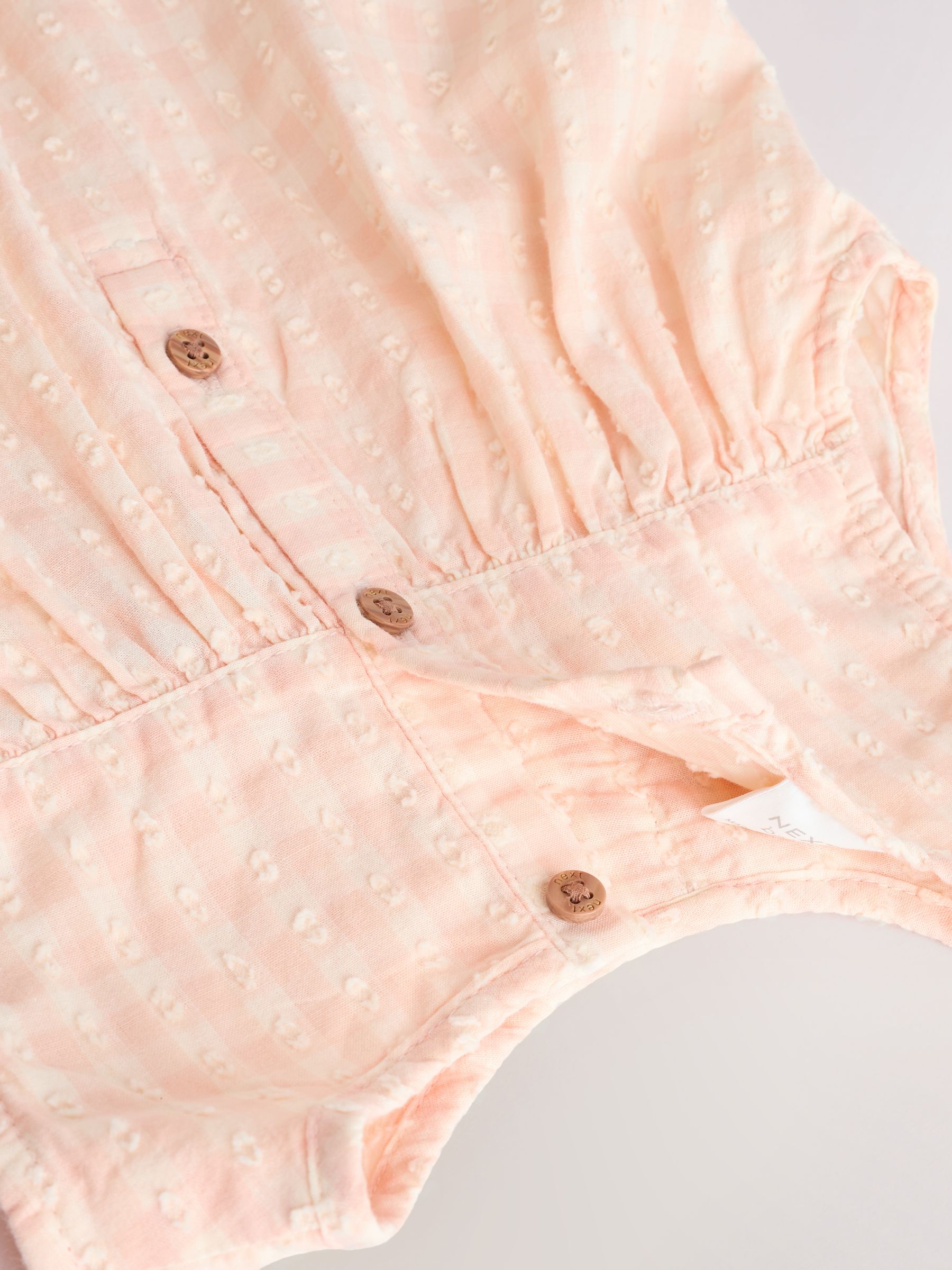 Perzikroze gingham-ruit - Babyromper met ruches (0mnd-2jr)