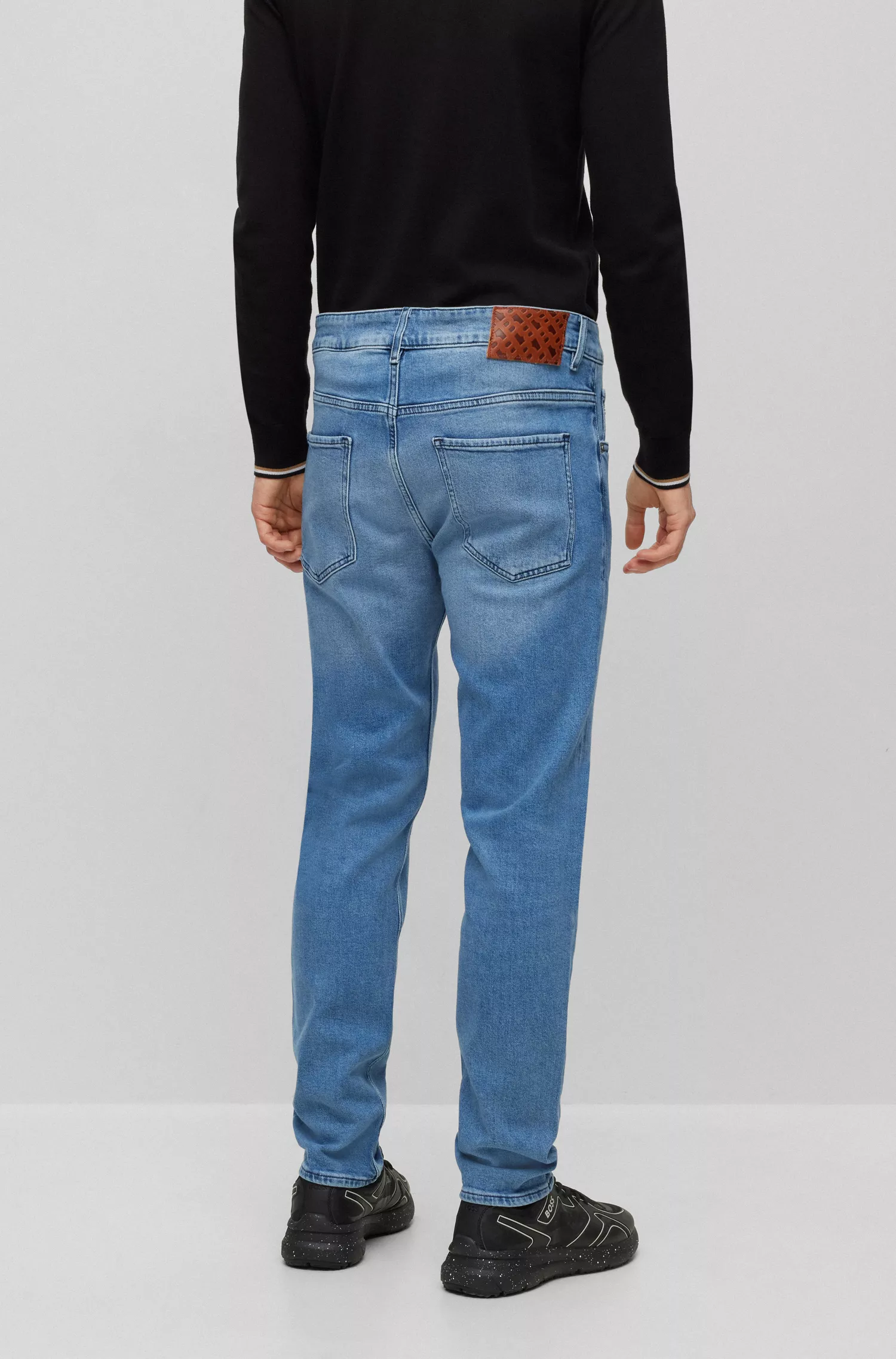 Calça jeans BOSS preta, corte afunilado, em denim azul vibrante com elasticidade confortável.