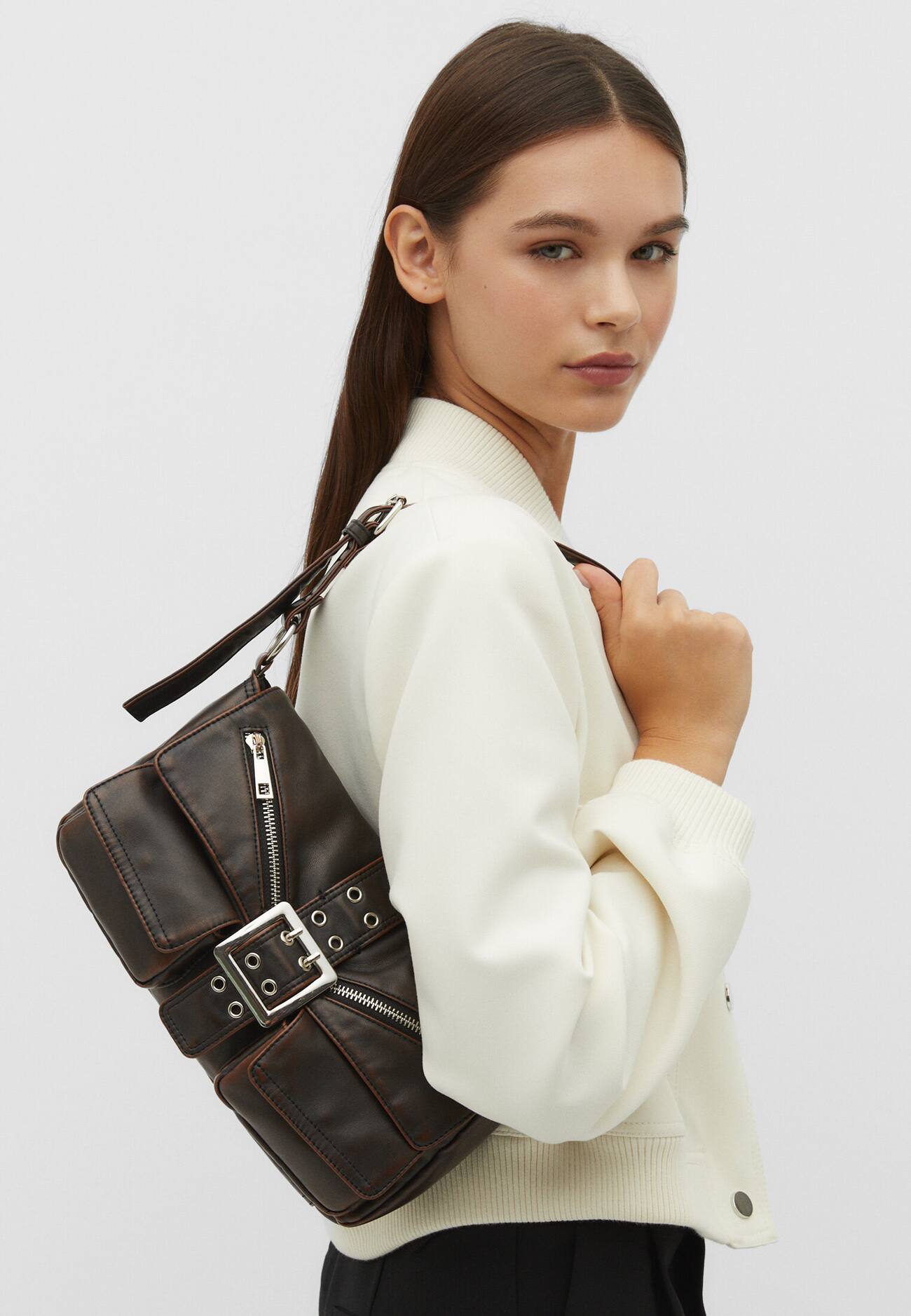 Bolsa de ombro com acabamento desgastado e bolsos.