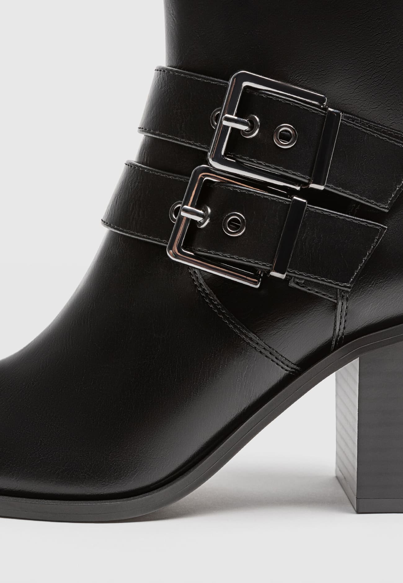 Botas pretas de cano curto com salto alto e fivelas.