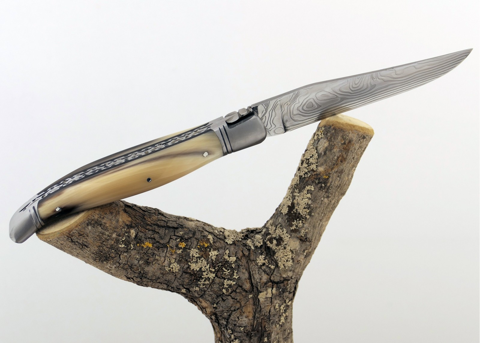 Couteau Laguiole prestige avec un manche en pointe de corne blonde et mitres en acier inoxydable et lame Damas