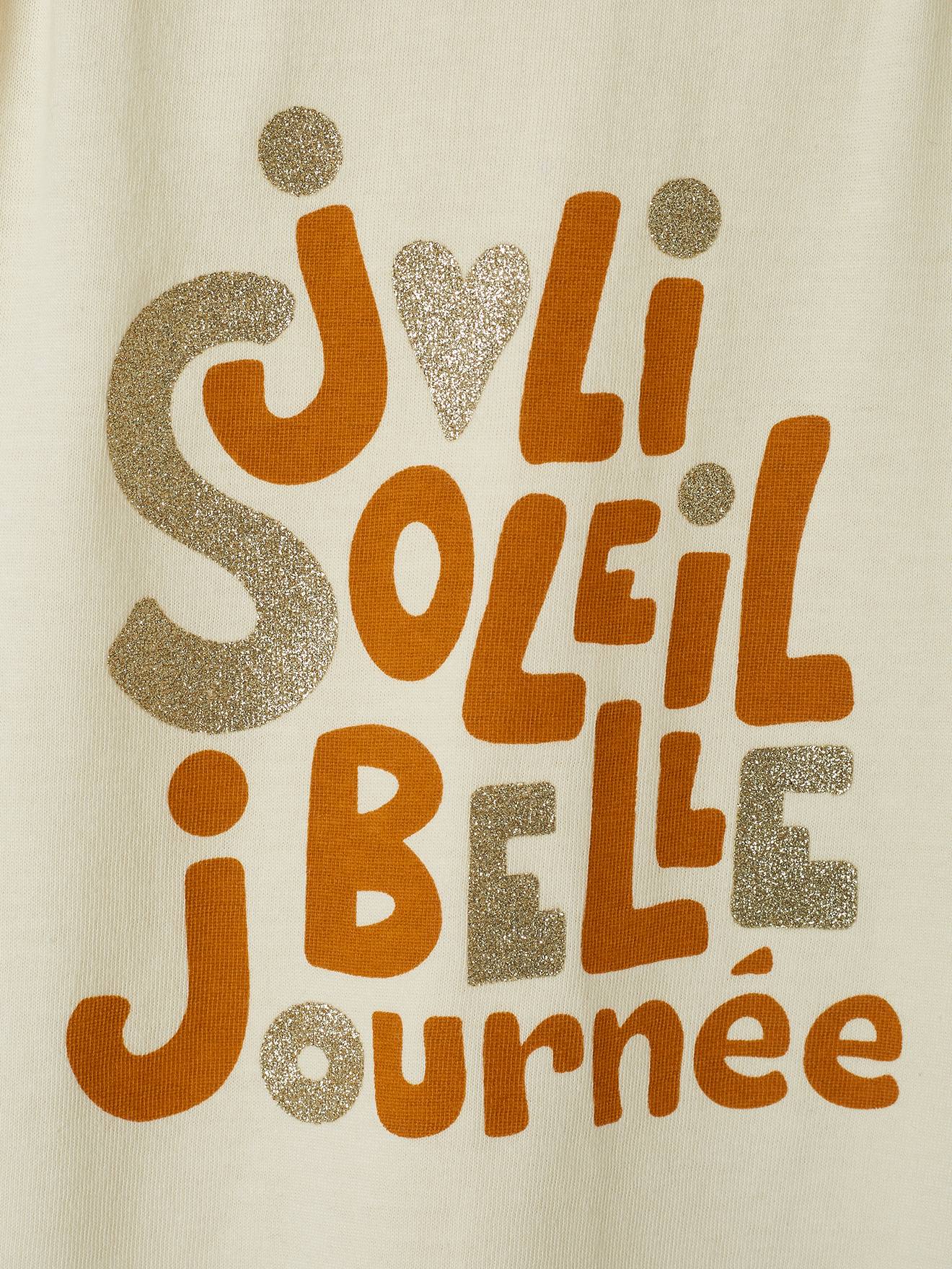 Camiseta infantil bege cru com estampa iridescente e ombros franzidos.