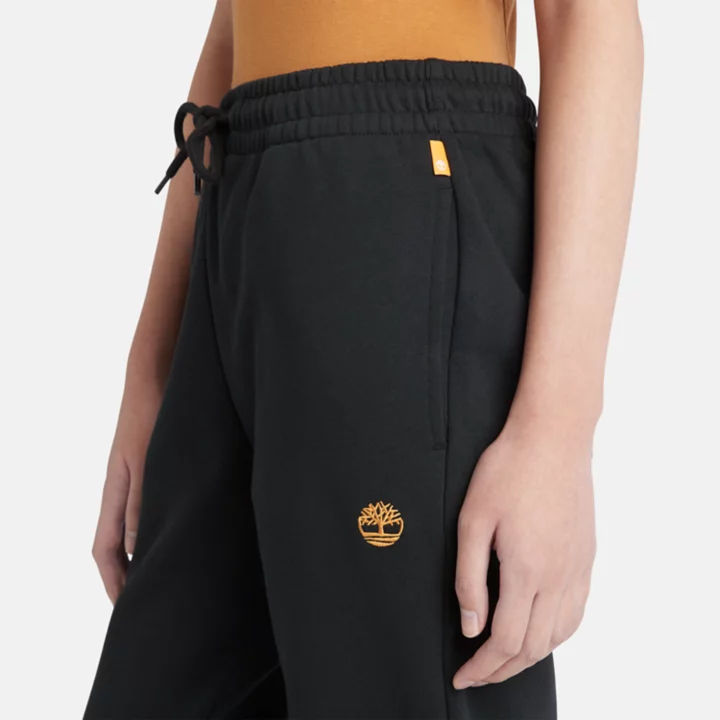 Calça de fato de treino feminina preta com bordado de árvore.