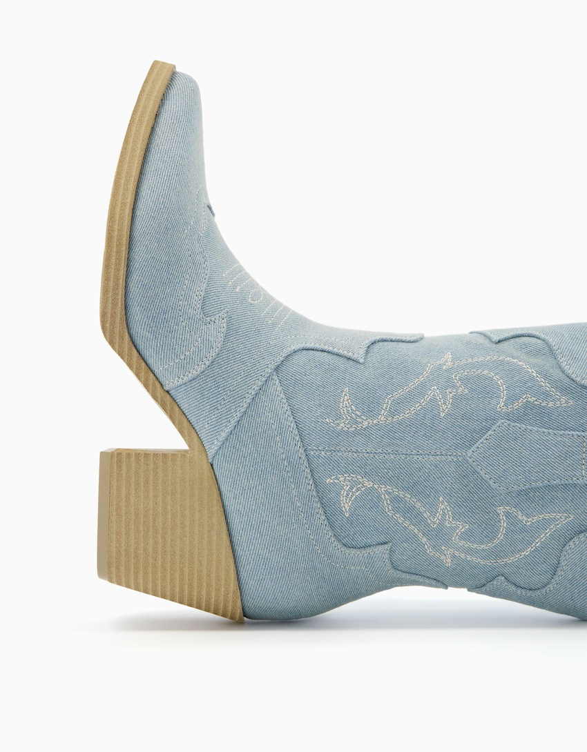 Botas de cano curto estilo cowboy em jeans com salto.