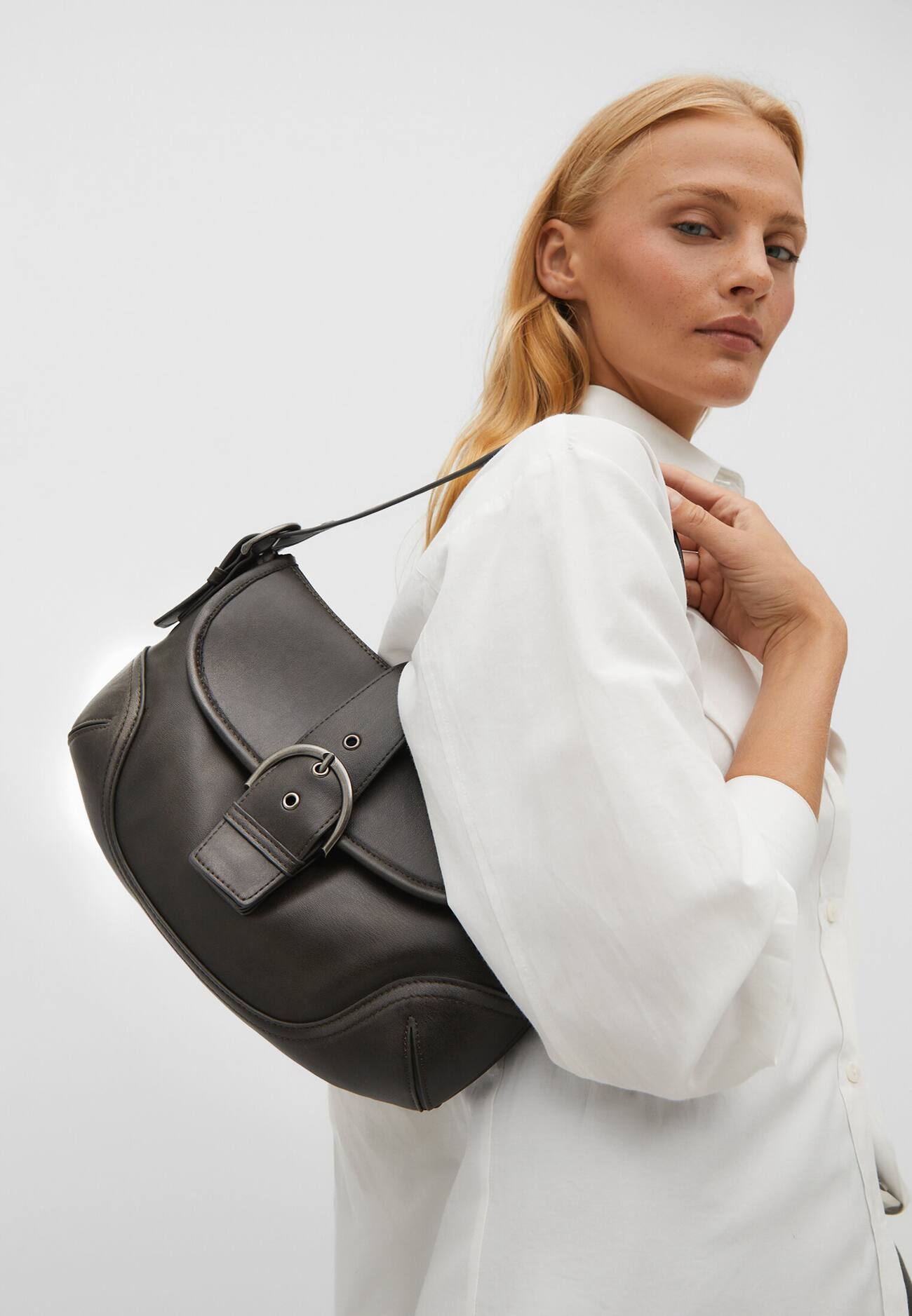 Bolsa de ombro com acabamento desgastado e fivela.