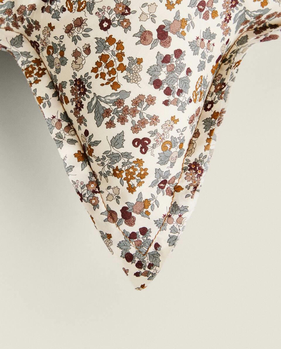 Almofada infantil em formato de estrela, em tecido com estampa floral.