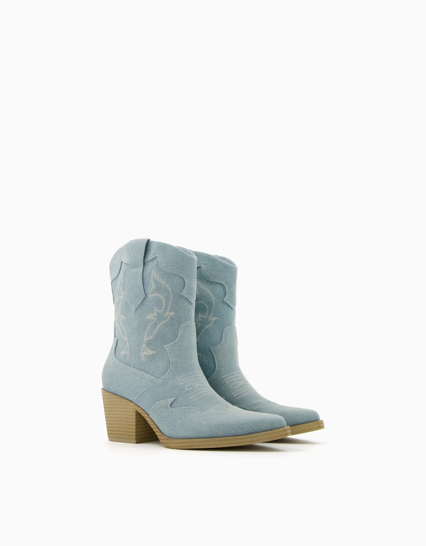 Botas de cano curto estilo cowboy em jeans com salto.