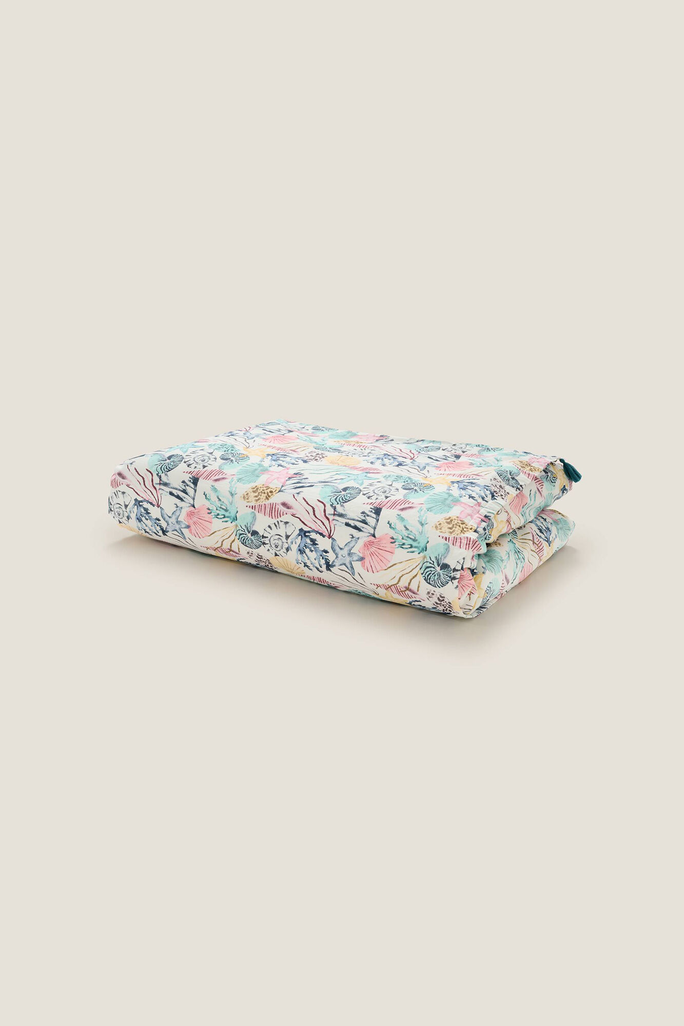 Toalha de praia estampada com conchas e tecido atoalhado.