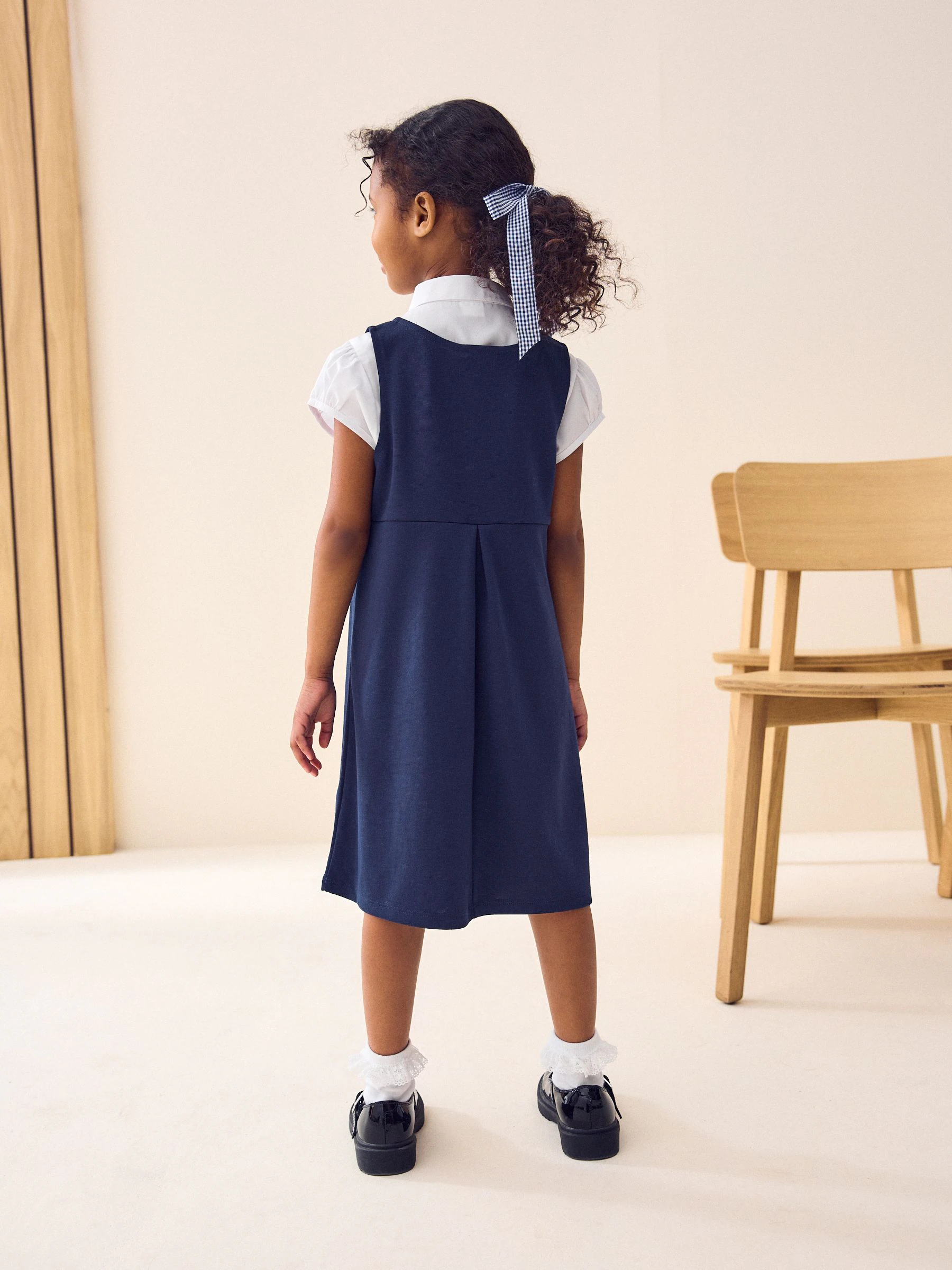 Marineblauw - Jersey stretch schoolovergooier met strik (3-16 jr)