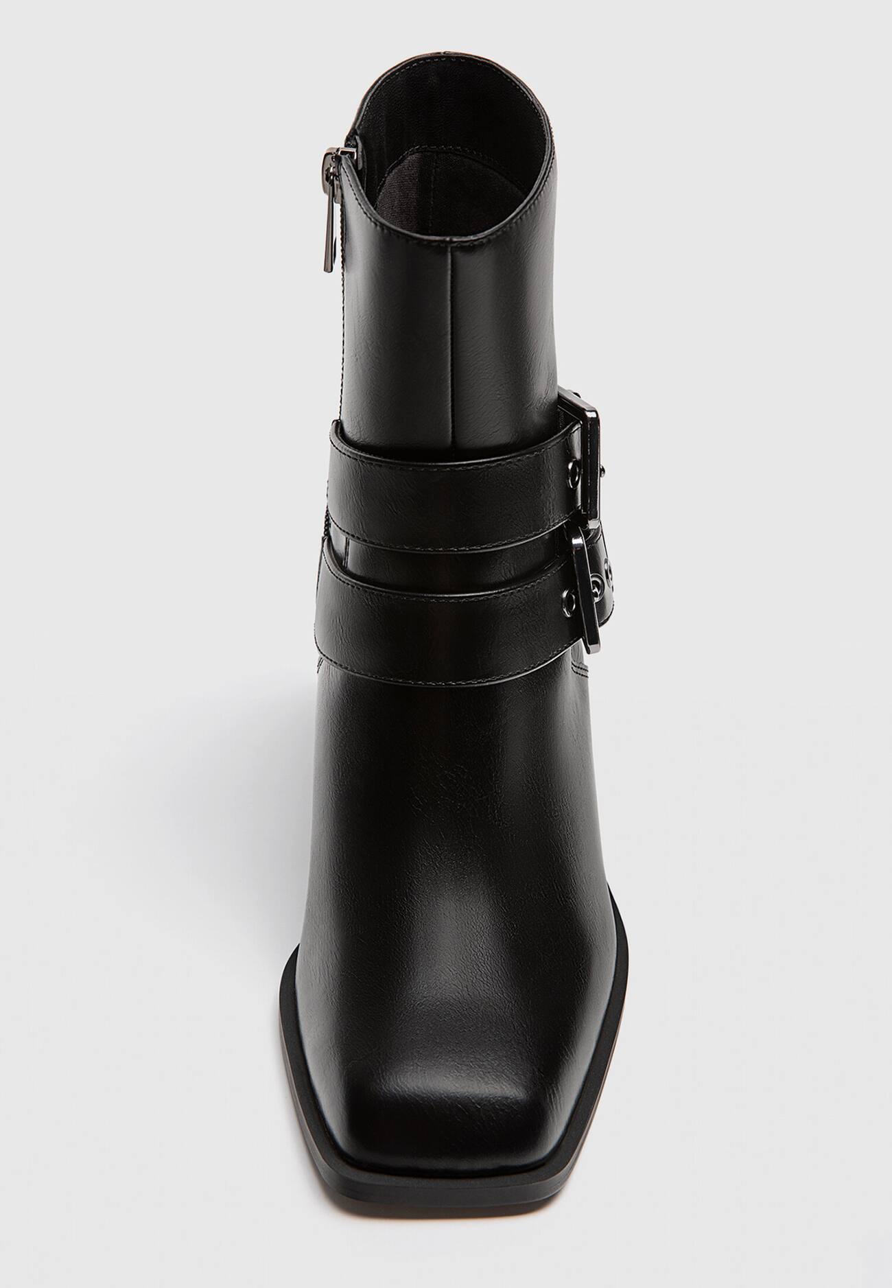 Botas pretas de cano curto com salto alto e fivelas.