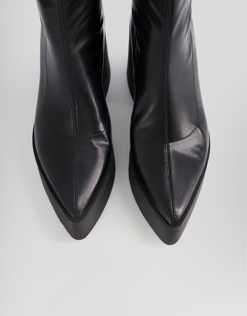 Botas de cano curto com plataforma e salto alto e bico fino.