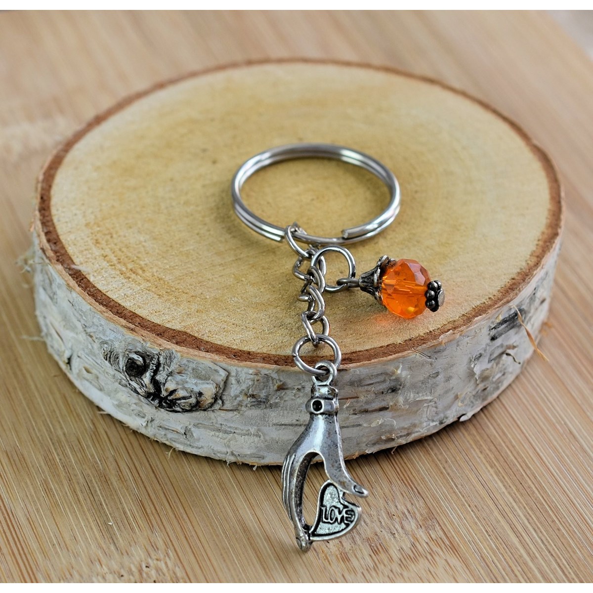 Porte-clés main qui tient un coeur love argentée et perle à facettes orange