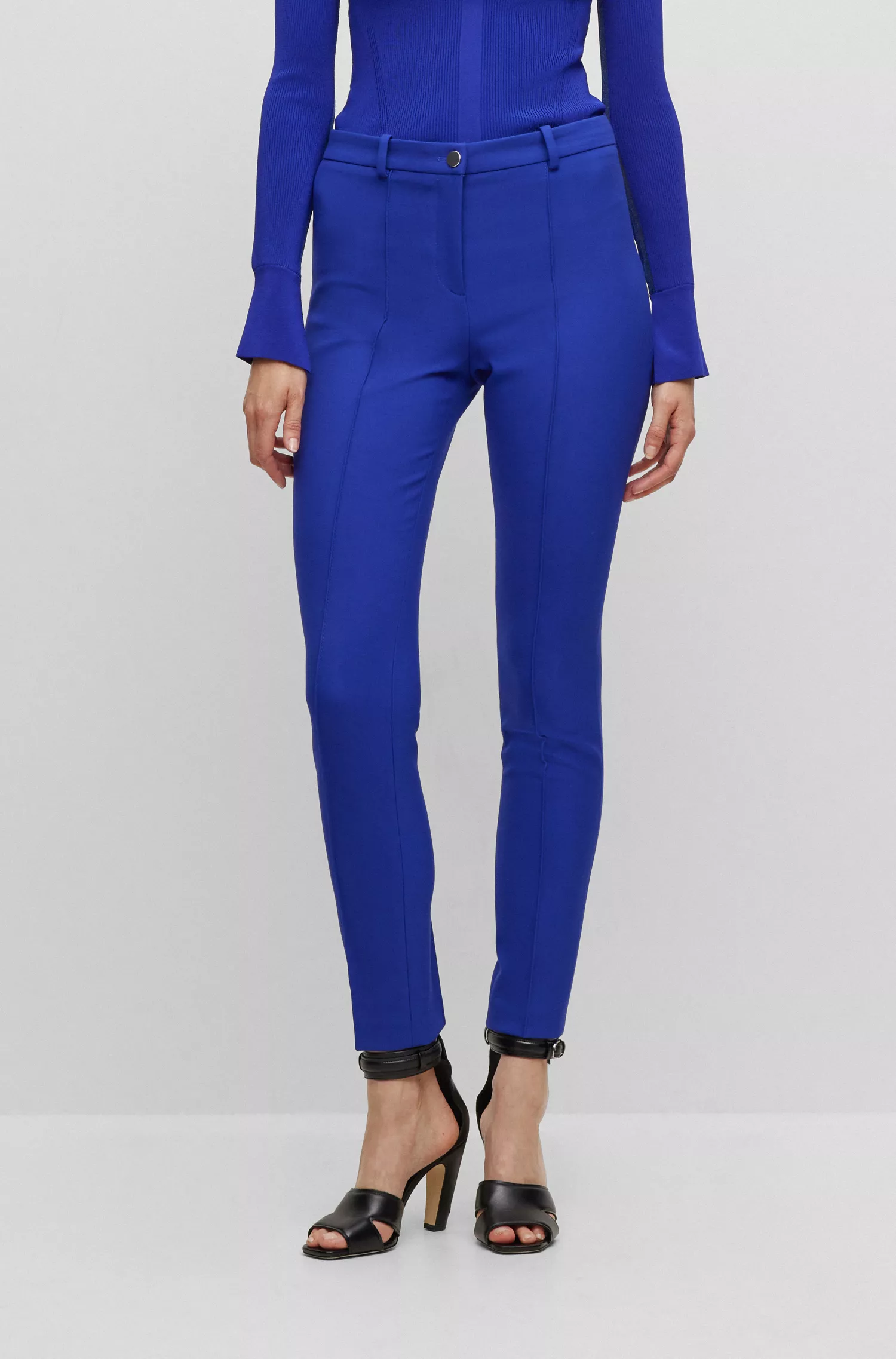 Calça BOSS preta, corte slim, em tecido elástico com pregas.