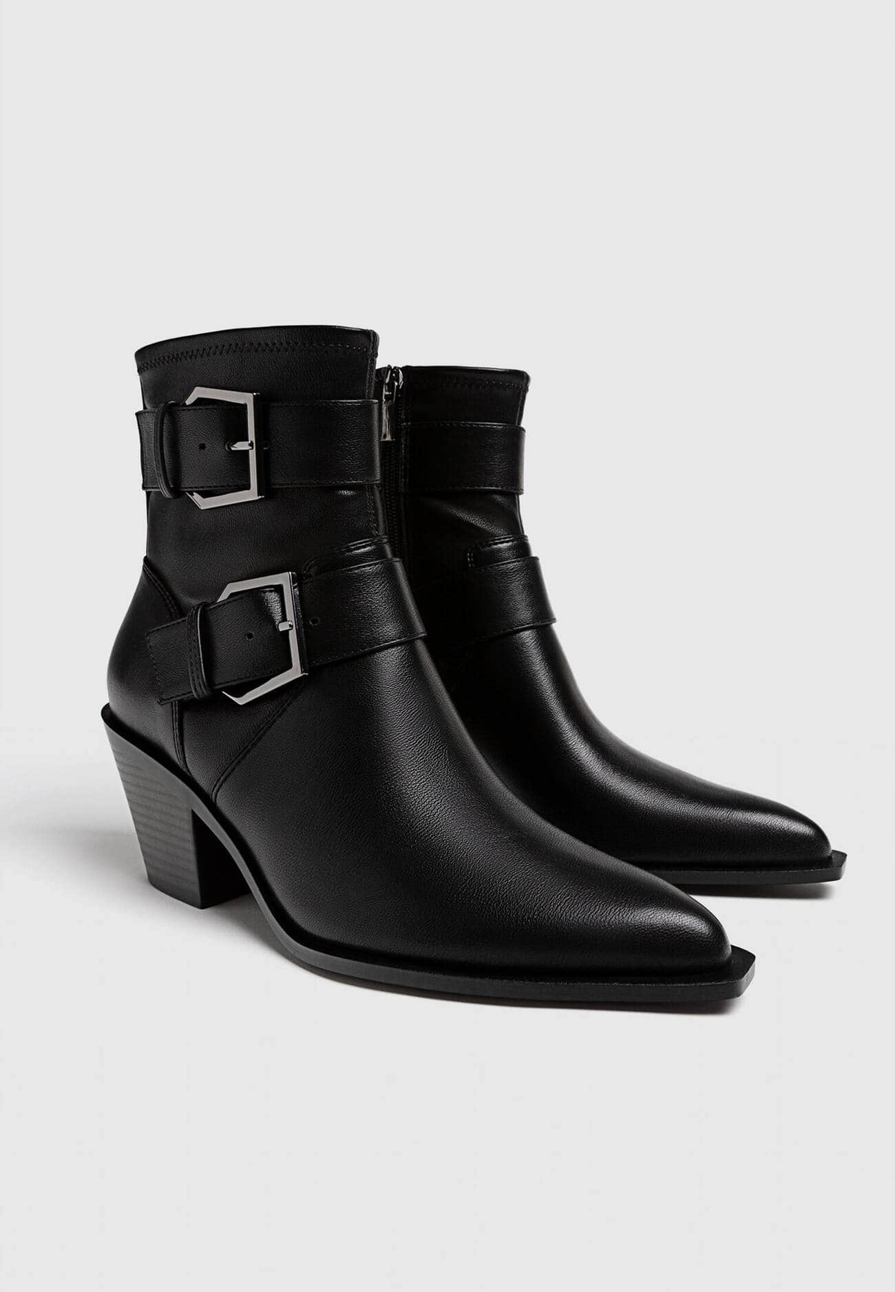 Botas pretas de cano curto com salto alto e fivelas.
