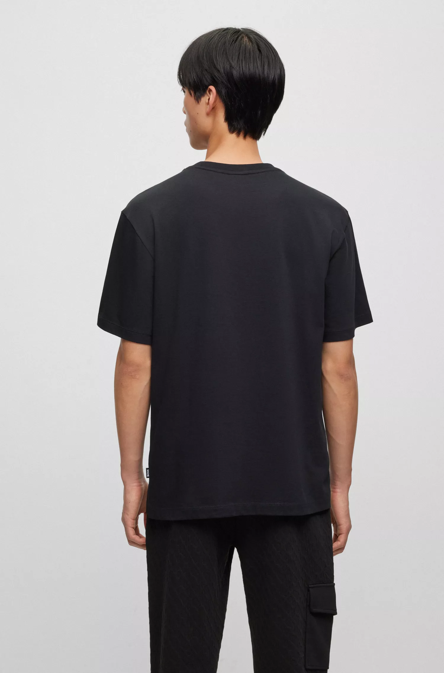 Camiseta BOSS preta em malha de algodão com monogramas estampados em cores variadas.