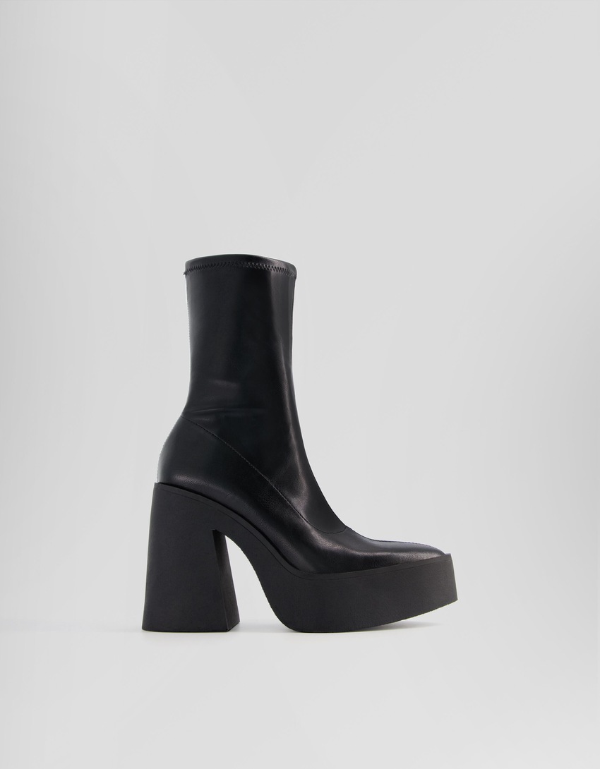 Botas de cano curto com plataforma e salto alto e bico fino.