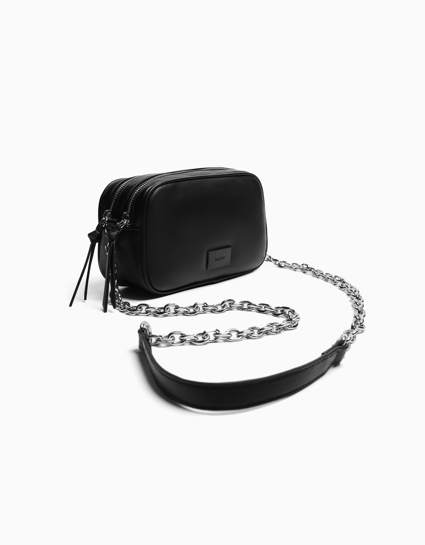 Bolsa transversal com fecho duplo de zíper e corrente.