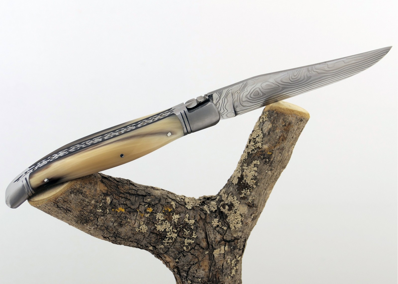 Couteau Laguiole prestige avec un manche en pointe de corne blonde et mitres en acier inoxydable et lame Damas
