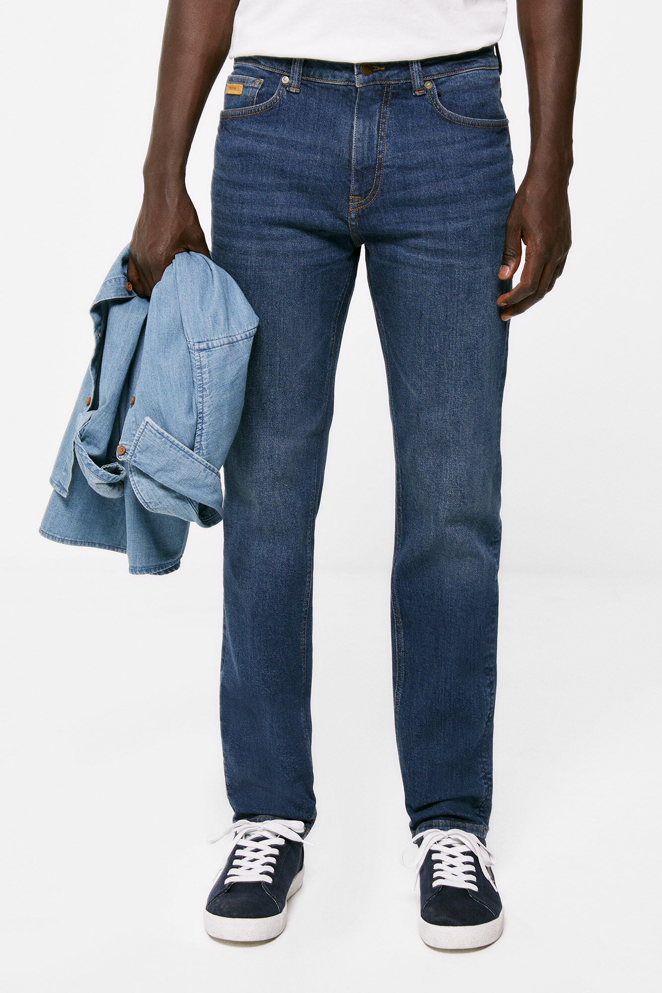Calça jeans slim, lavagem clara escura, com detalhes desgastados.