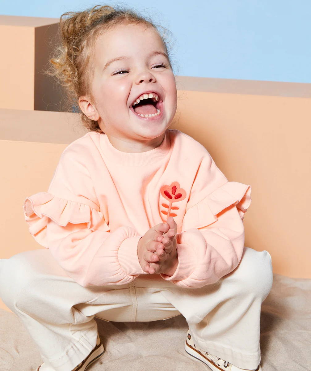 sweat bébé fille en fibres recyclées orange pâle avec volants et fleur brodée