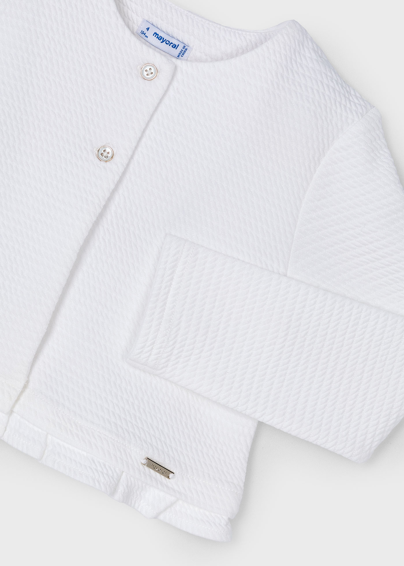 Rebecca tricotou um vestido branco estruturado para menina.