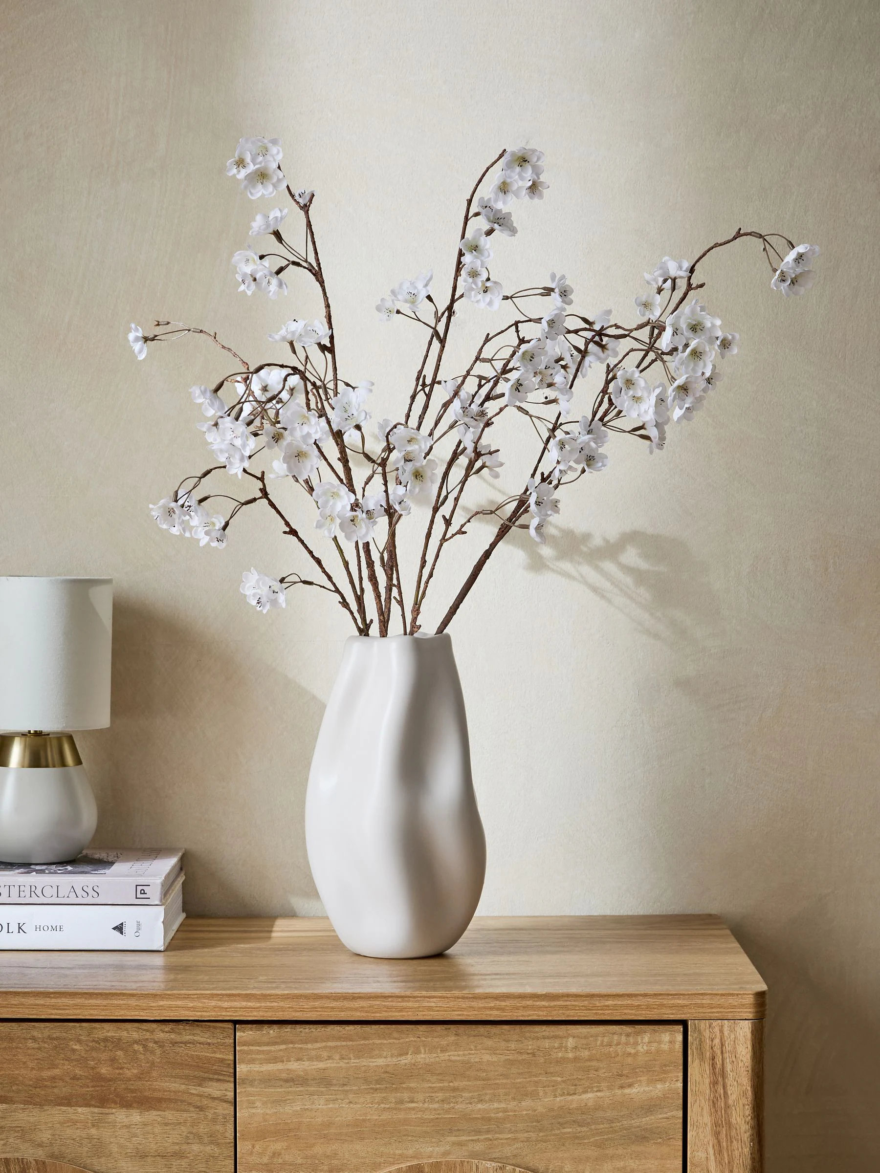 Kunstbloesemstelenarrangement in witte keramische vaas