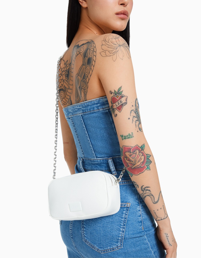 Bolsa transversal com fecho duplo de zíper e corrente.
