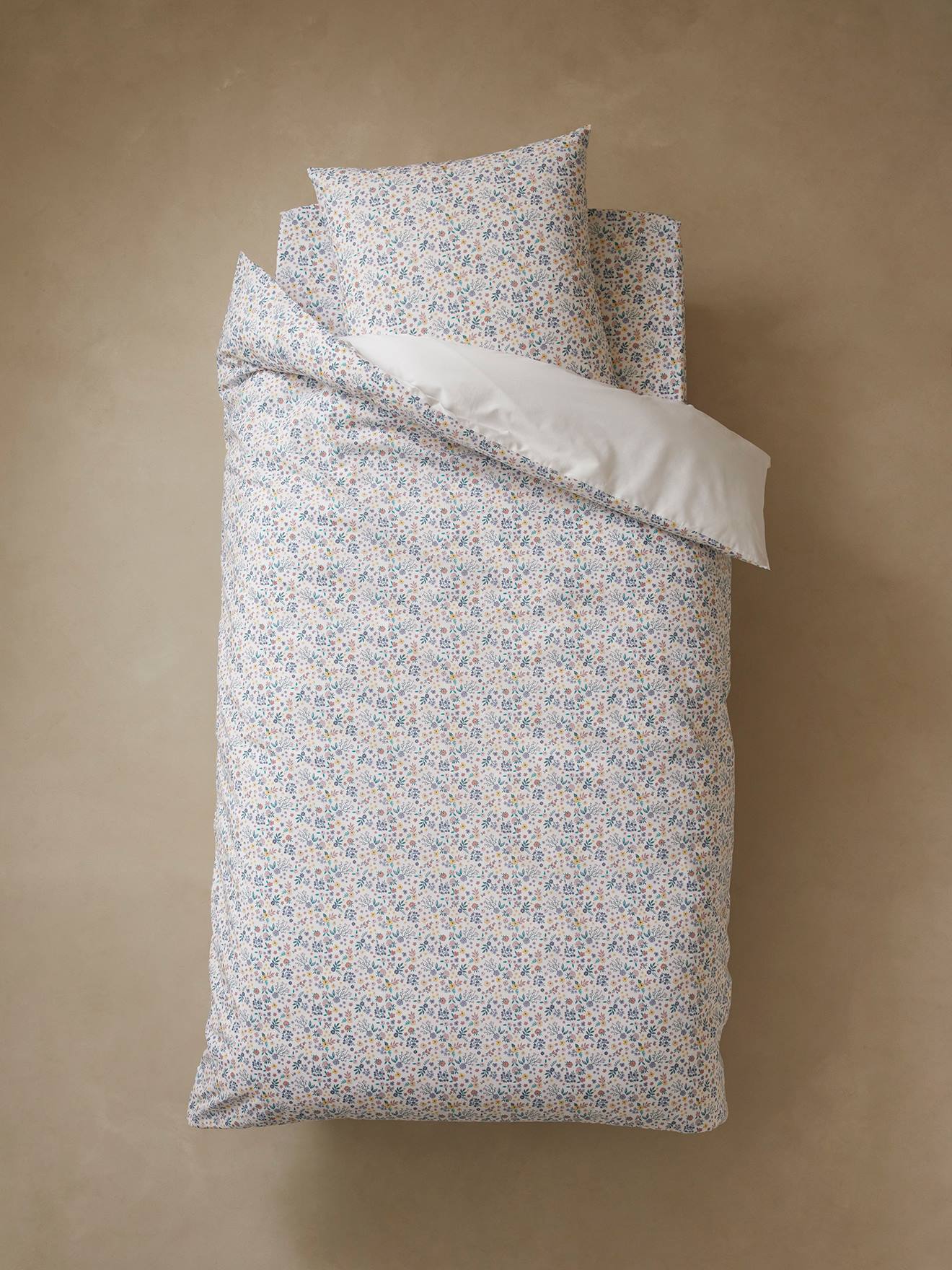 Conjunto infantil de capa de edredom e fronha, liso em branco claro e lilás com estampas.