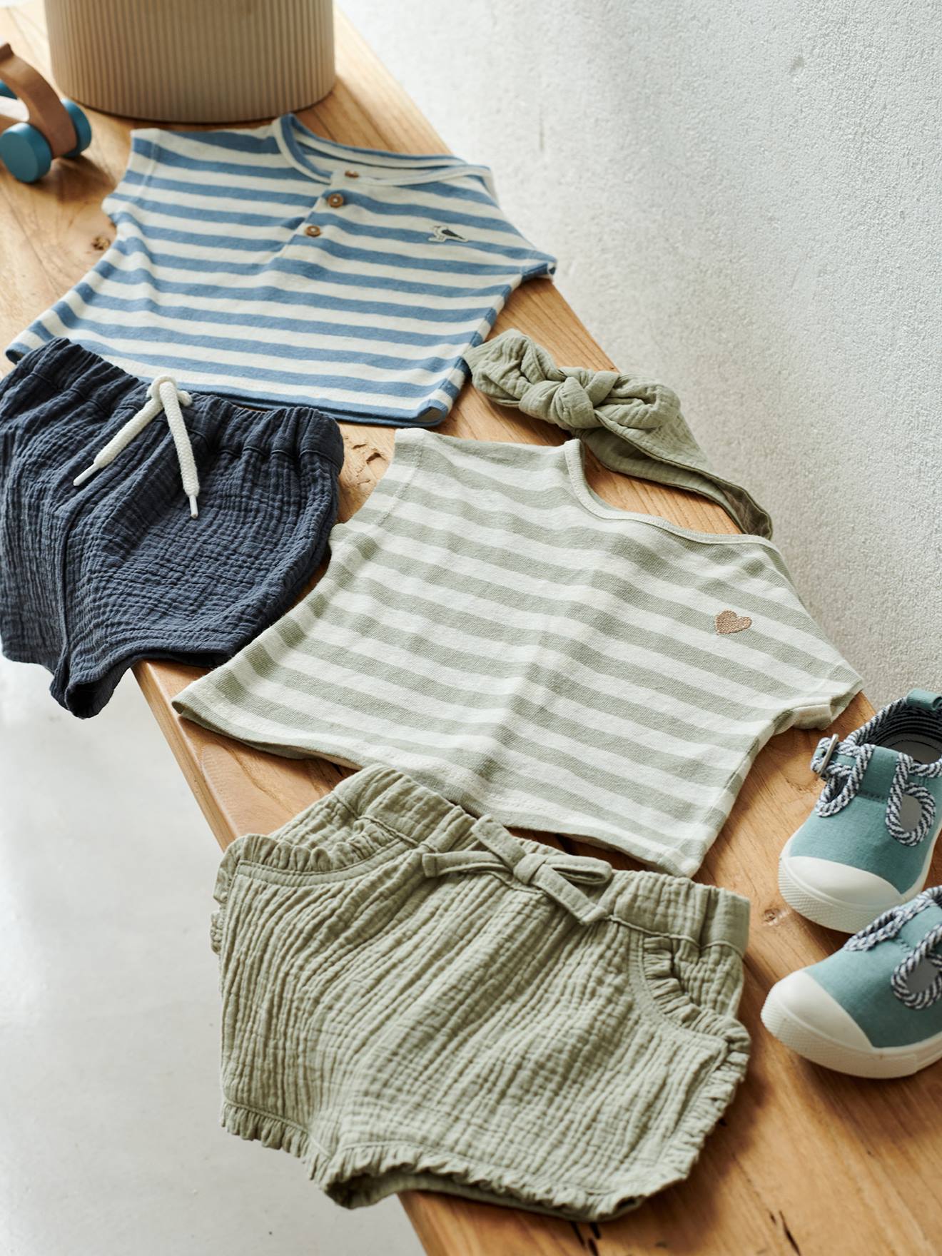 Roupa de bebê: shorts, camiseta listrada e faixa de cabelo verde-acinzentada.