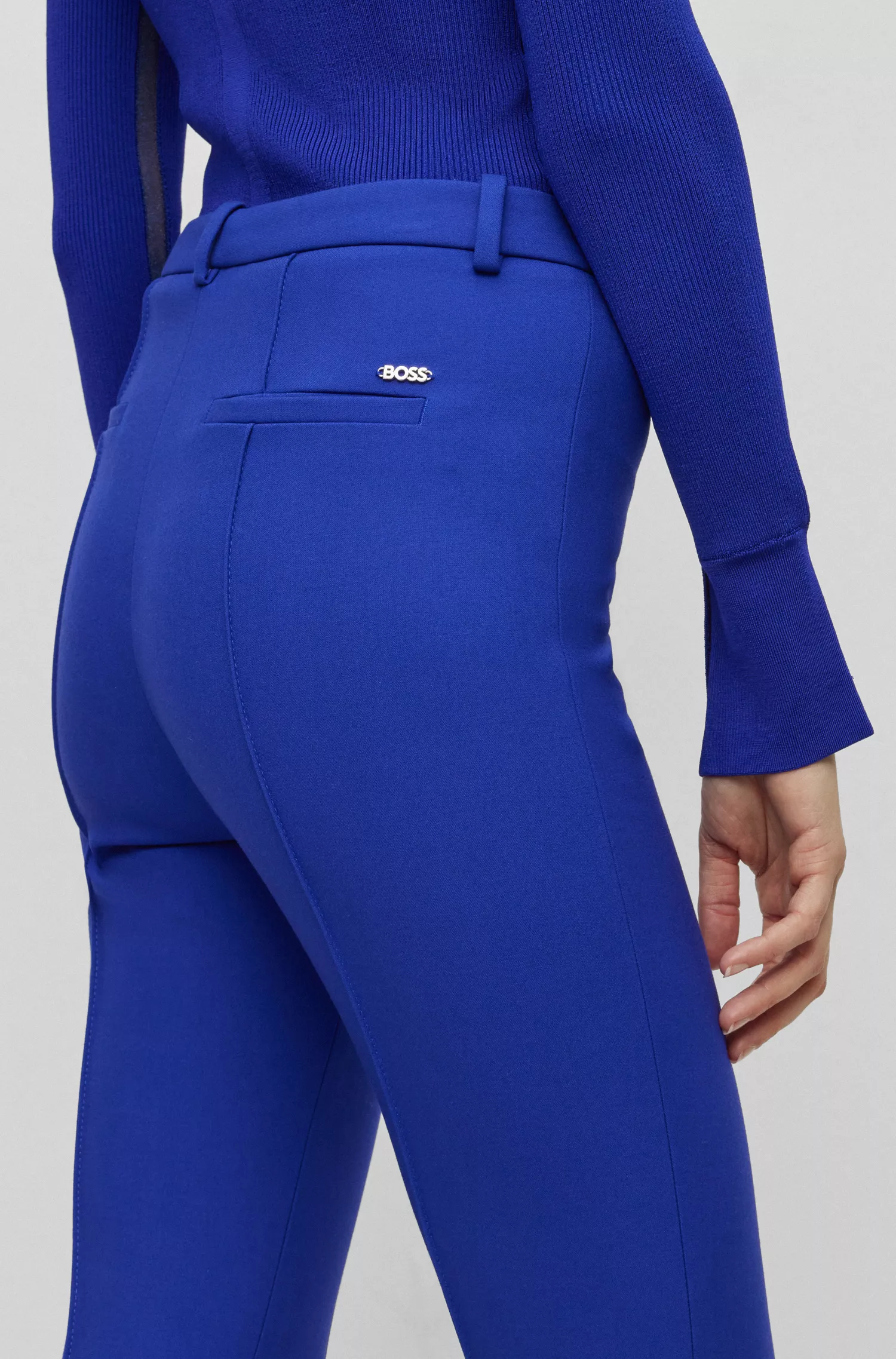 Calça BOSS preta, corte slim, em tecido elástico com pregas.